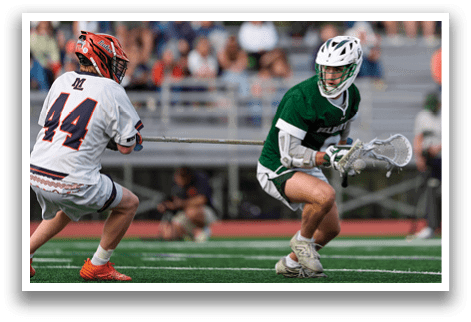 A man in a green shirt and white shorts is holding a lacrosse stick. Description generated by AI