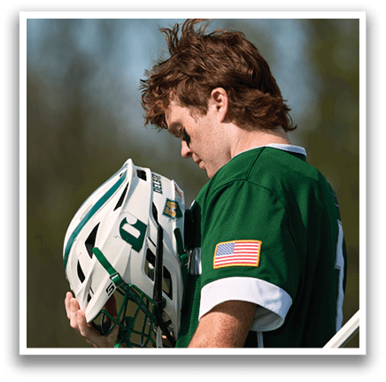 A man wearing a green and white shirt with a helmet on his head. Description generated by AI