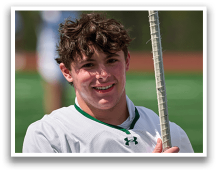 A young man holding a lacrosse stick. Description generated by AI