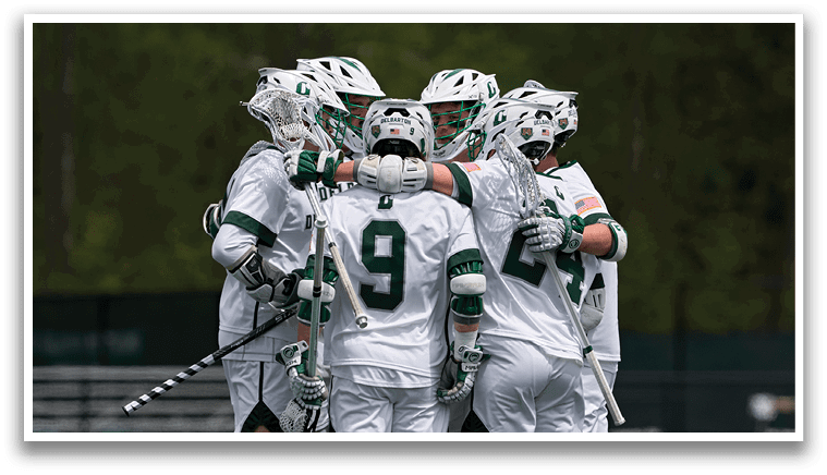 Four men wearing white uniforms and holding hockey sticks. Description generated by AI