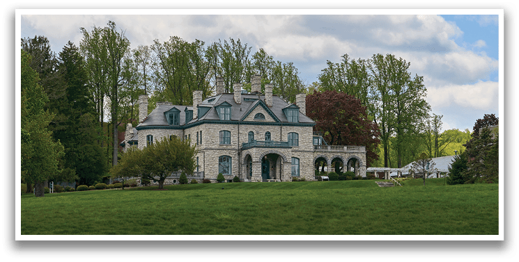 A large white house with a gray roof and black trim. Description generated by AI