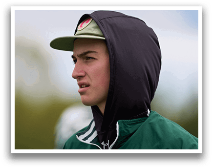 A man wearing a green jacket with a hood on his head. Description generated by AI
