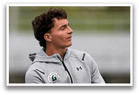 A man with curly hair and a gray jacket. Description generated by AI