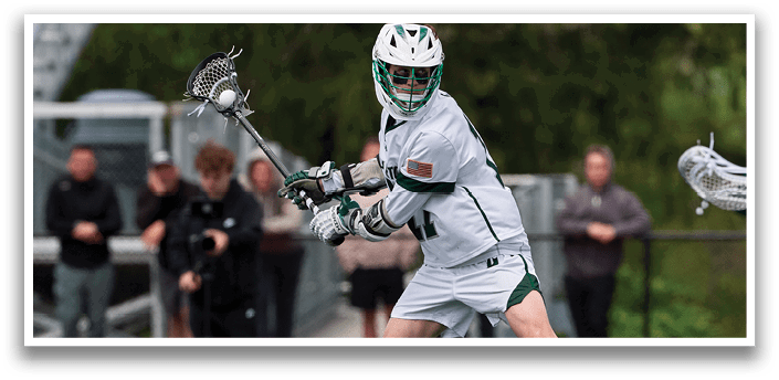 A man in a white uniform is holding a lacrosse stick. Description generated by AI