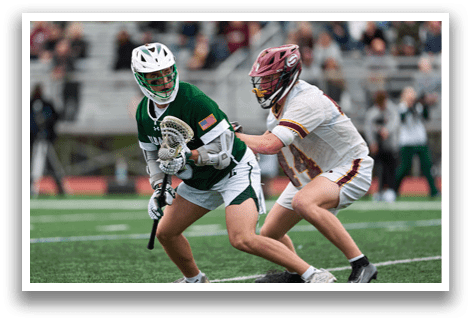 Two men playing lacrosse on a field. Description generated by AI