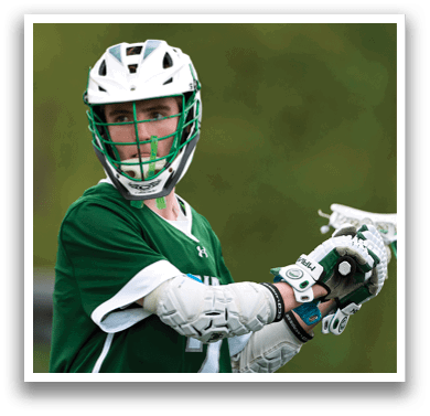 A man wearing a green and white shirt and holding a lacrosse stick. Description generated by AI