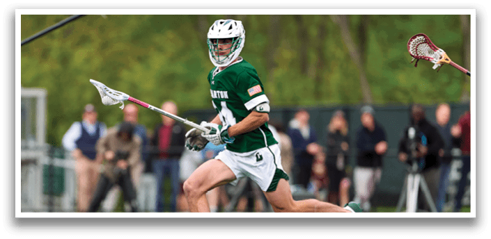 A man running with a lacrosse stick. Description generated by AI