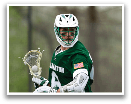 A man wearing a green and white shirt and white shorts holding a lacrosse stick. Description generated by AI