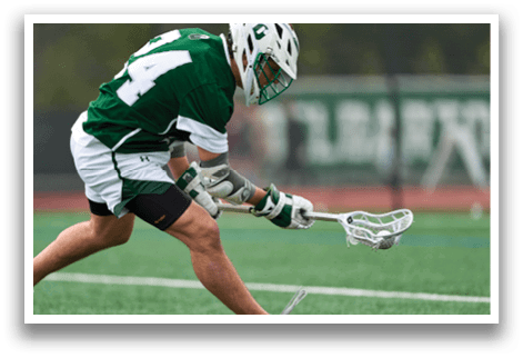 A man wearing a green and white uniform is playing lacrosse. Description generated by AI