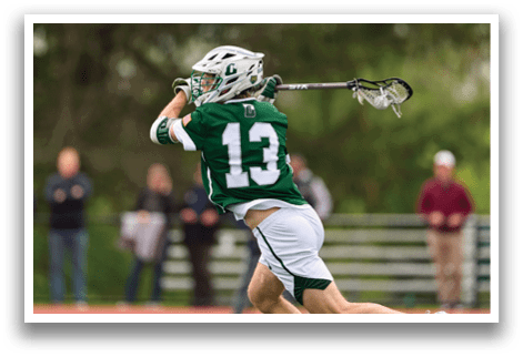 A man wearing a green and white jersey is playing lacrosse. Description generated by AI