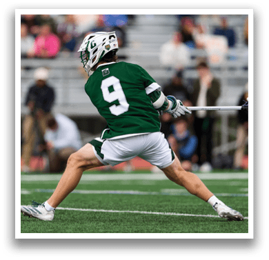 A man wearing a green and white uniform is running with a stick in his hand. Description generated by AI