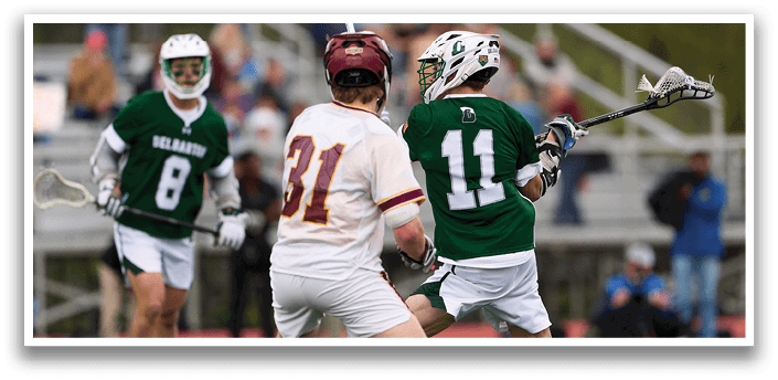 A man in a green shirt and white shorts is running with a lacrosse stick. Description generated by AI