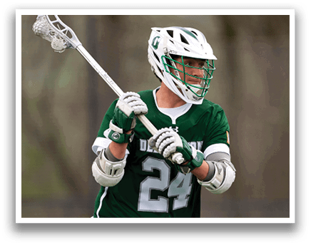 A man wearing a green and white jersey holding a lacrosse stick. Description generated by AI