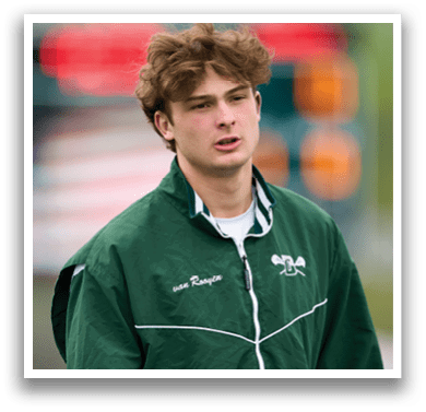 A man wearing a green jacket and holding a lacrosse stick. Description generated by AI