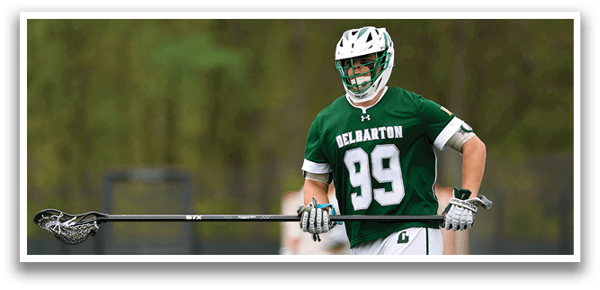 A man wearing a green and white shirt holding a lacrosse stick. Description generated by AI