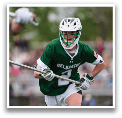 A man wearing a green shirt and white shorts is holding a stick. Description generated by AI