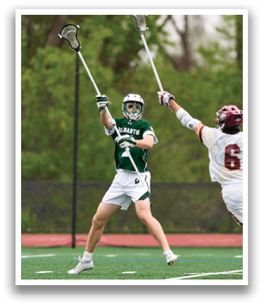 Two men playing lacrosse on a field. Description generated by AI