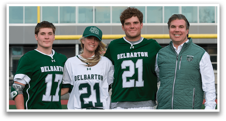A group of people standing in front of a football field. Description generated by AI