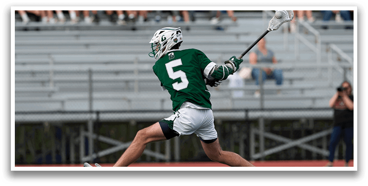 A man wearing a green and white uniform is running with a lacrosse stick. Description generated by AI