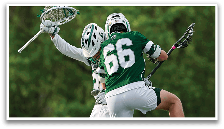Two men are playing lacrosse on a field. Description generated by AI