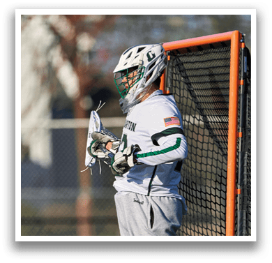 A man wearing a white and green uniform is standing in front of a net. Description generated by AI