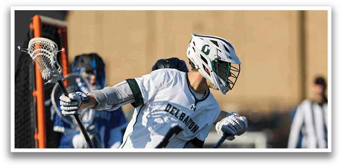 A man wearing a white and green jersey is running with a lacrosse stick. Description generated by AI