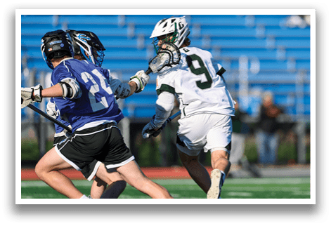Two men playing lacrosse on a field. Description generated by AI