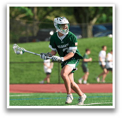 A man wearing a green and white uniform is holding a lacrosse stick. Description generated by AI
