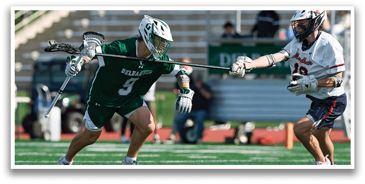 A man in a green jersey is running with a lacrosse stick. Description generated by AI