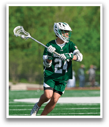 A man wearing a green and white jersey is holding a lacrosse stick. Description generated by AI