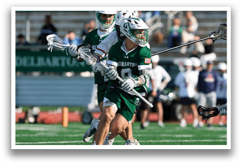 Two men playing lacrosse on a field. Description generated by AI