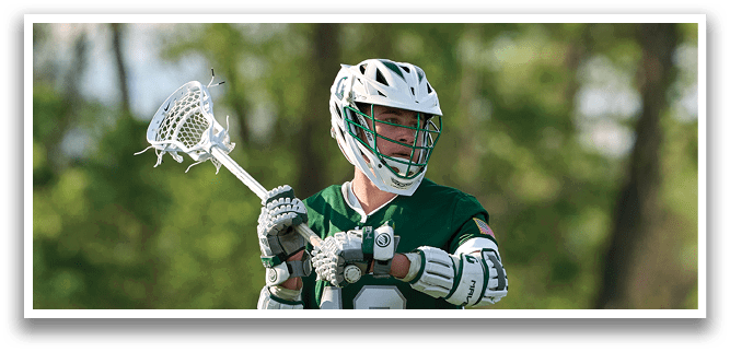 A man wearing a green and white shirt and holding a lacrosse stick. Description generated by AI