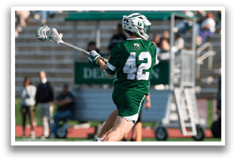 A man in a green jersey is holding a lacrosse stick. Description generated by AI
