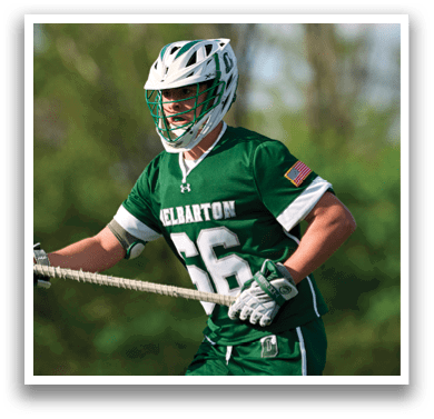 A man wearing a green shirt and white shorts is holding a stick. Description generated by AI