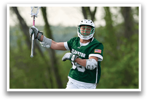 A man wearing a green and white shirt holding a lacrosse stick. Description generated by AI