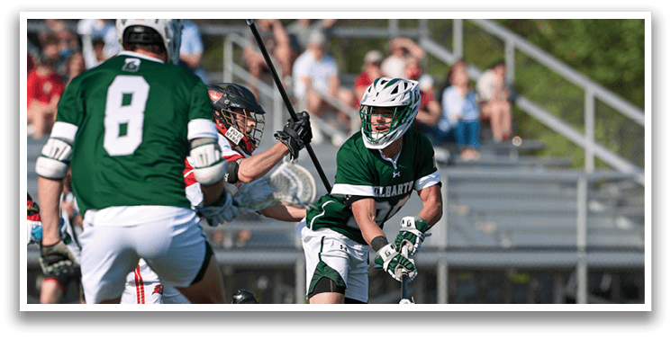 A man in a green and white uniform is running with a lacrosse stick. Description generated by AI