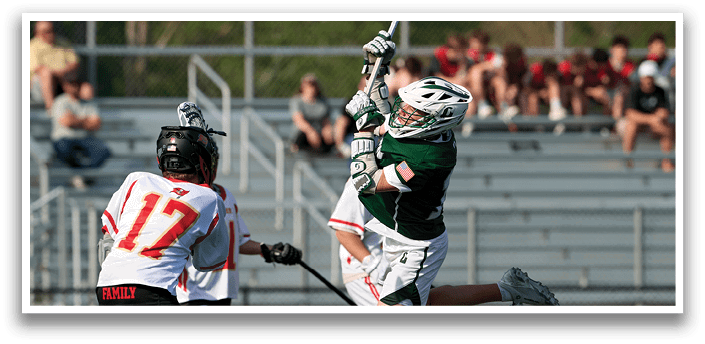 A man in a green shirt is holding a lacrosse stick. Description generated by AI