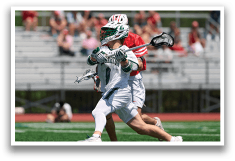 A man in a green and white uniform is running with a lacrosse stick. Description generated by AI