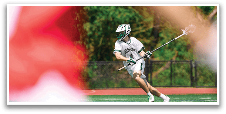 A man is playing lacrosse on a field. Description generated by AI