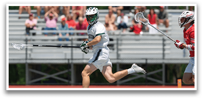 A man in a white uniform is running with a stick. Description generated by AI
