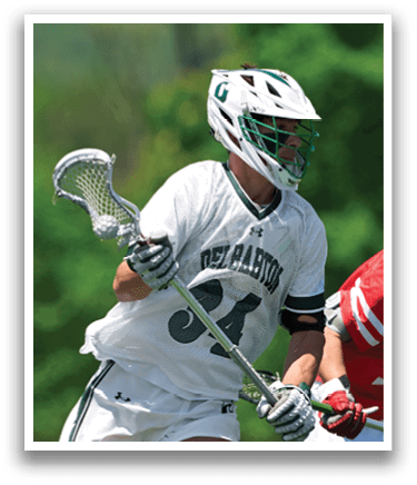 A man wearing a white shirt and green shorts holding a stick. Description generated by AI