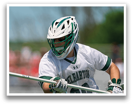 A man wearing a green and white uniform holding a lacrosse stick. Description generated by AI