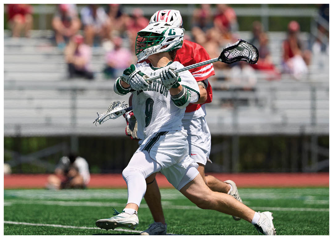 A man in a green and white uniform is running with a lacrosse stick. Description generated by AI