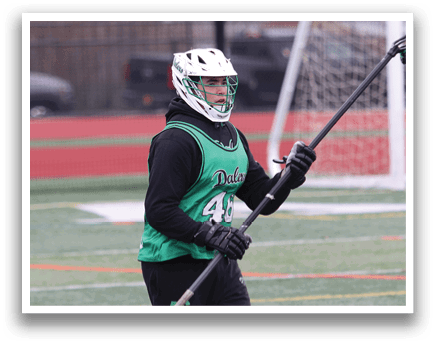A person wearing a green and white uniform is holding a lacrosse stick and walking on a field. AI generated content