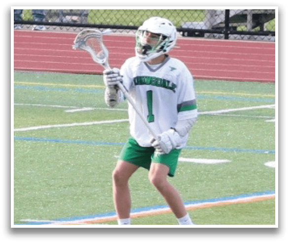 A young man wearing a white jersey and green shorts is holding a lacrosse stick and standing on a field. AI generated content