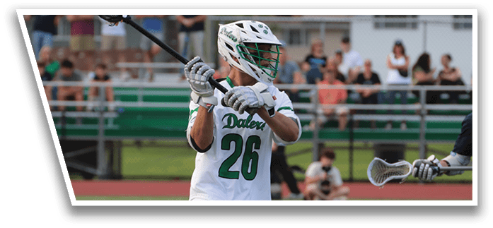 A man in a green and white uniform holding a lacrosse stick. Description generated by AI