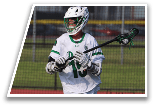 A man wearing a white shirt and white shorts is holding a black and green lacrosse stick. Description generated by AI