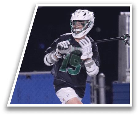 A man in a green shirt and white shorts is playing lacrosse. Description generated by AI