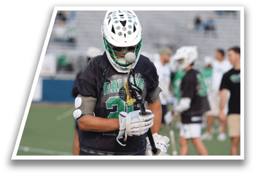 A man wearing a green and black jersey holding a lacrosse stick. Description generated by AI