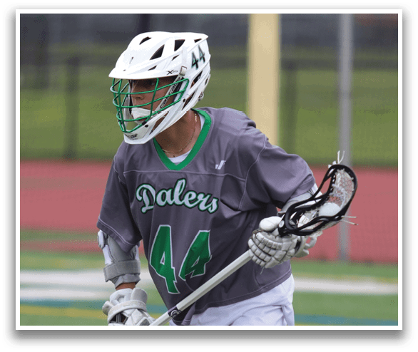 A man wearing a grey and green shirt and white shorts is holding a lacrosse stick. AI generated content